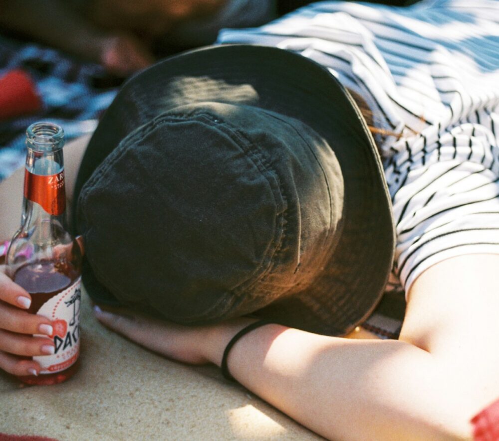 a person laying on a blanket with a bottle of beer