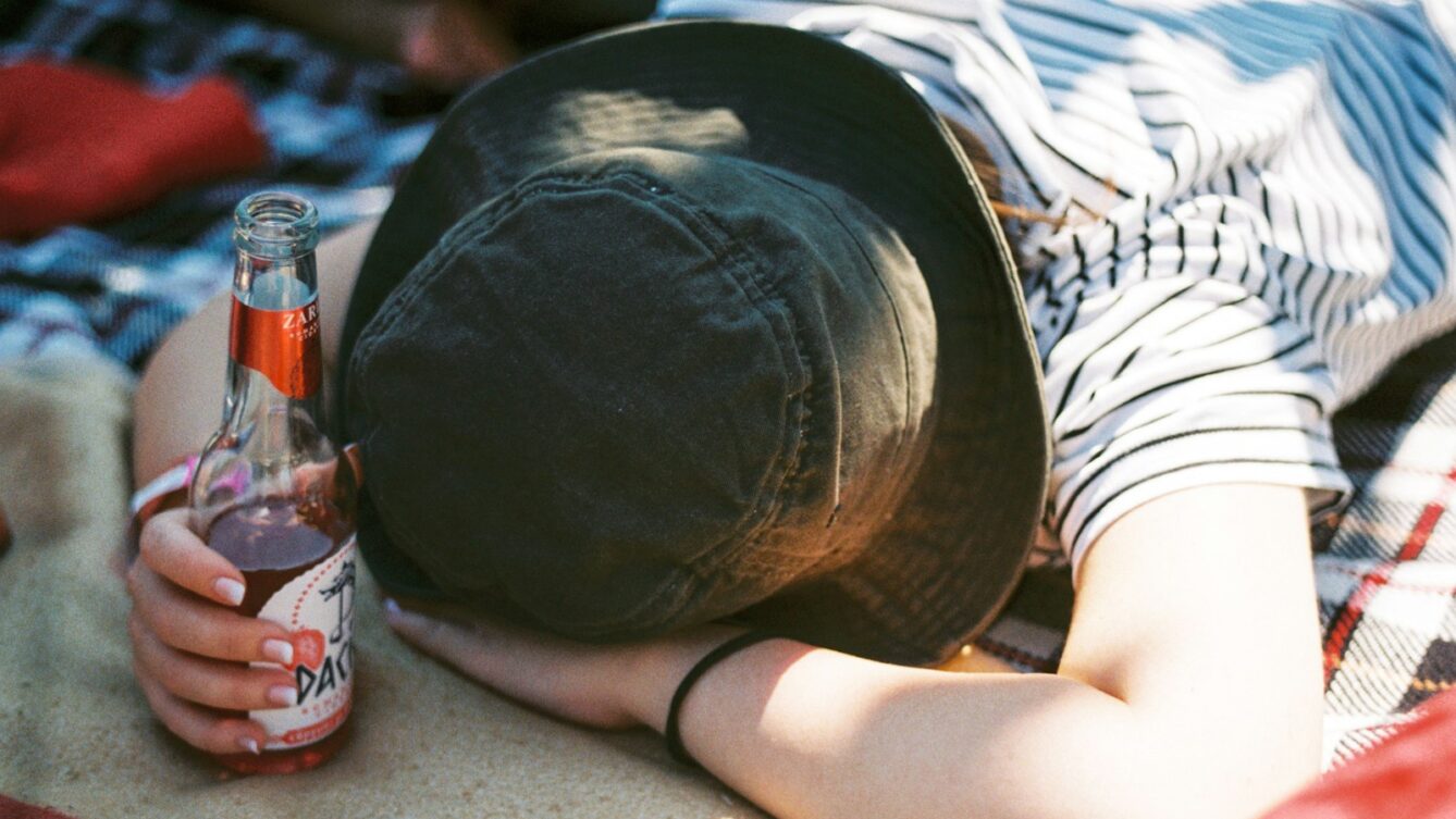 a person laying on a blanket with a bottle of beer
