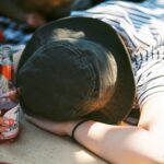 a person laying on a blanket with a bottle of beer