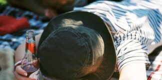 a person laying on a blanket with a bottle of beer