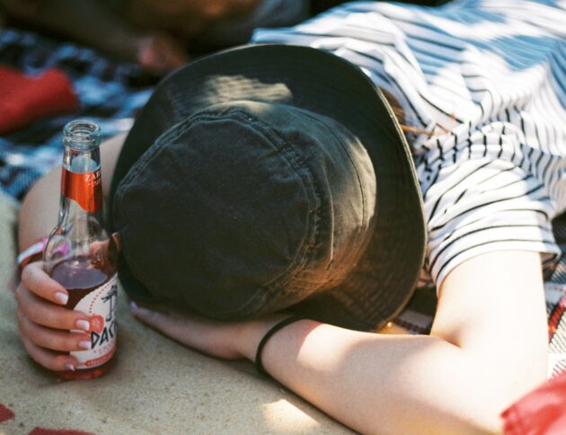 a person laying on a blanket with a bottle of beer