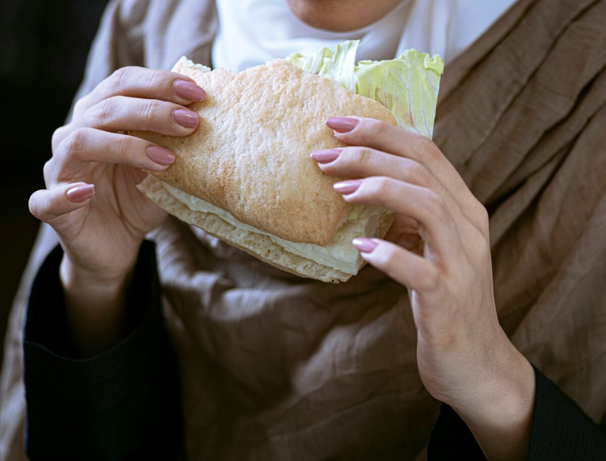 person in white shirt holding bread