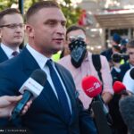 meżczyzna w garniturze przed mikrofonami dziennikarzy