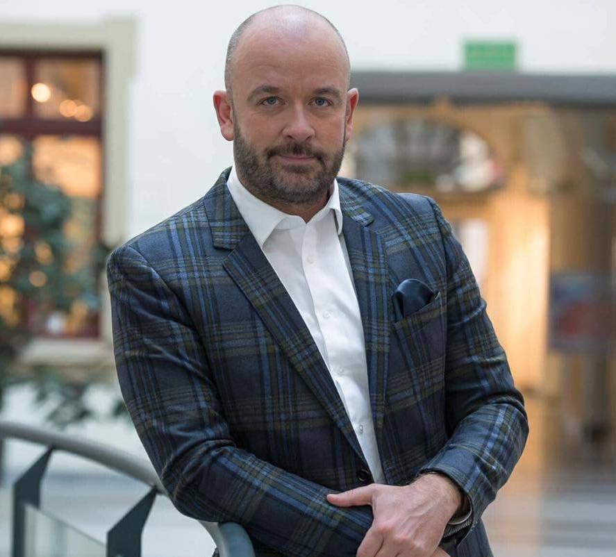 mężczyzna w marynarce opiera się o balustradę