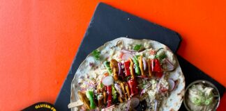 pizza with green vegetable and meat on black plate