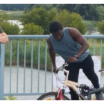 umundurowani ludzie zatrzymują na moście osobę na rowerze