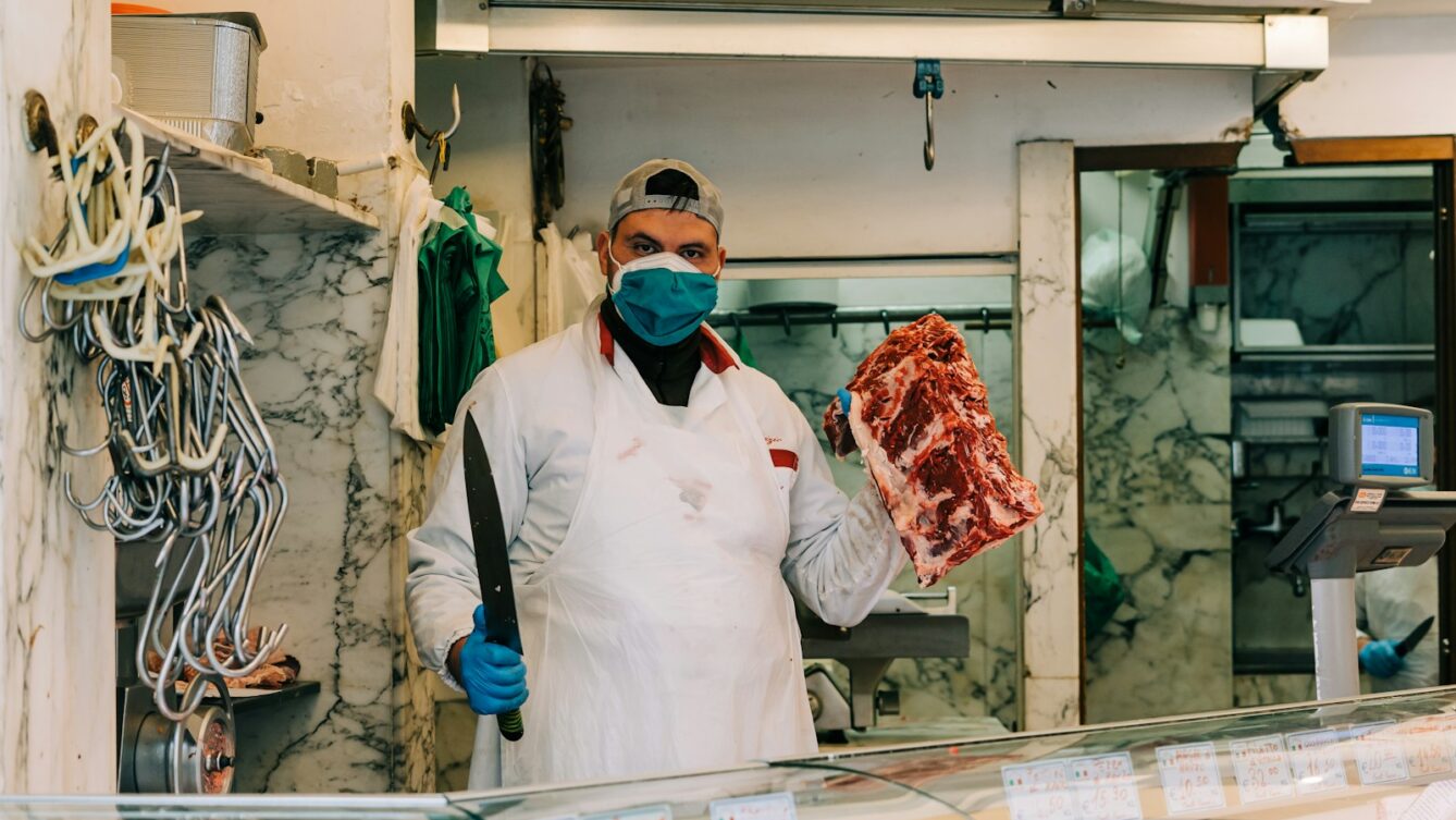 man in white dress shirt and black necktie holding raw meat