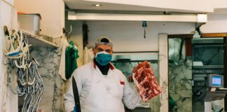 man in white dress shirt and black necktie holding raw meat