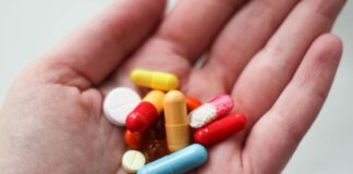 orange and white medication pill on persons hand