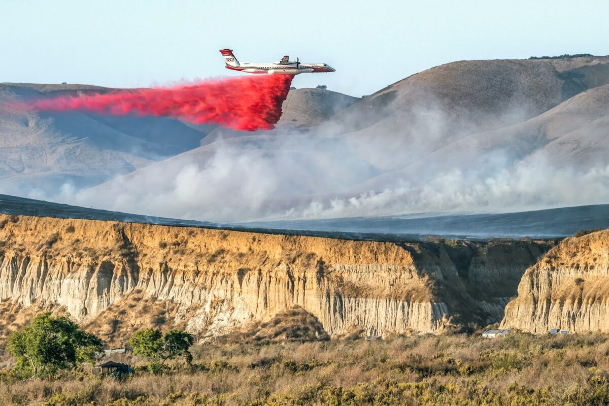 A red plane is flying over a mountain