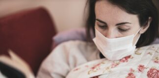 kobieta chora na grypę leży w łóżku i czyta książkę