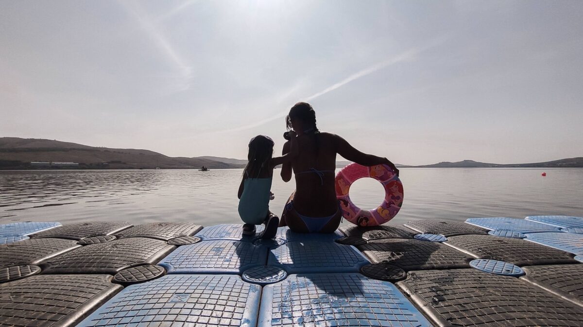 a woman and child sitting on a surfboard in the water