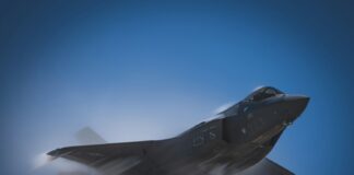 a fighter jet flying through a blue sky