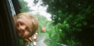 dziecko wychylające się zza samochodowego okna/ fot: Anton Luzhkovsky/ Unsplash