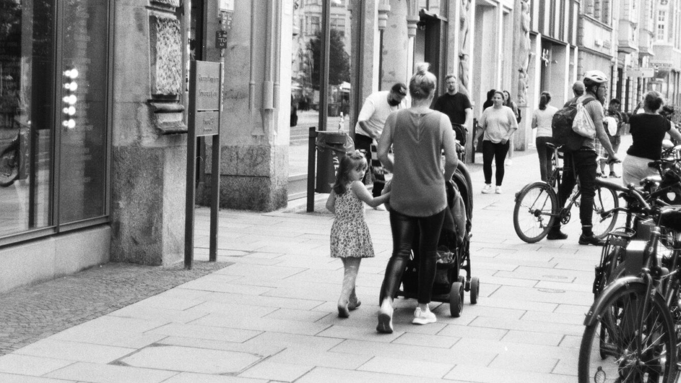 czarno-białe zdjęcie ulicy z przechodniami w centrum kobieta z dzieckiem/ fot: Maryna Nikolaieva/ Unsplash