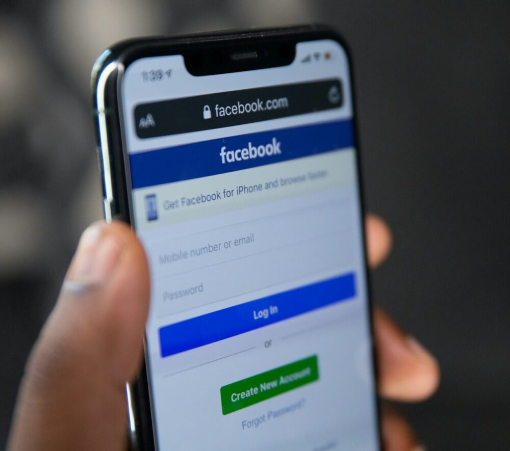 Ekran telefonu z logiem Meta i ostrzeżeniem o podejrzanych reklamach/ fot: Solen Feyissa/ Unsplash