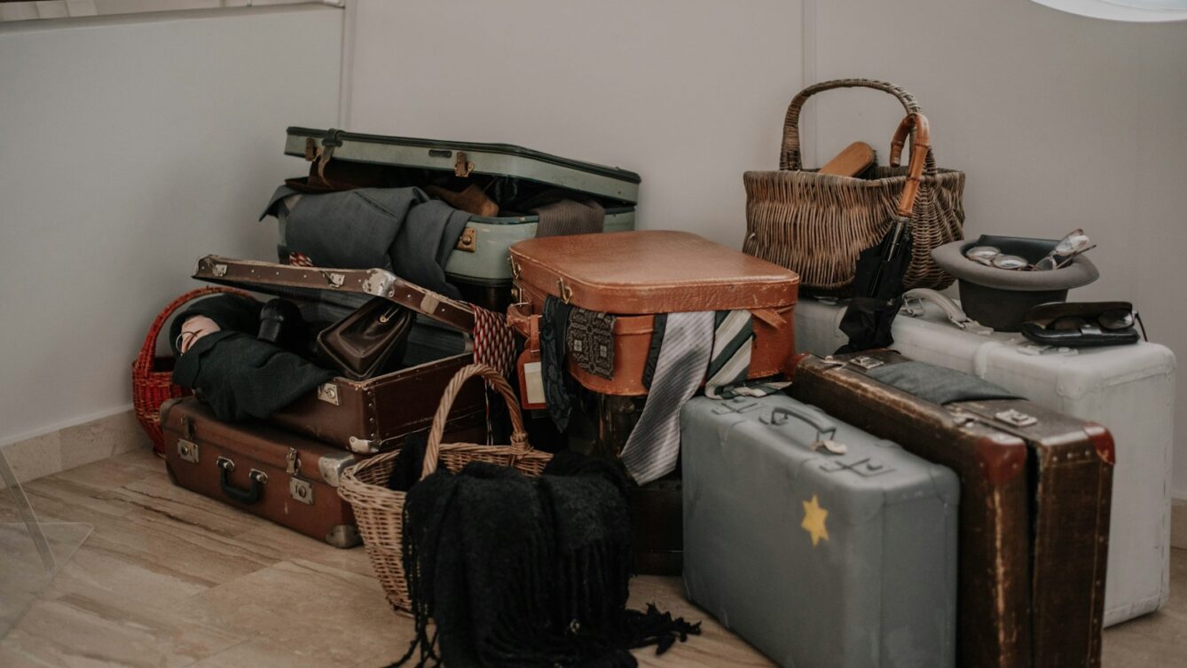 Uszkodzony bagaż po locie – sterta zniszczonych walizek w pomieszczeniu obsługi reklamacji linii lotniczych.