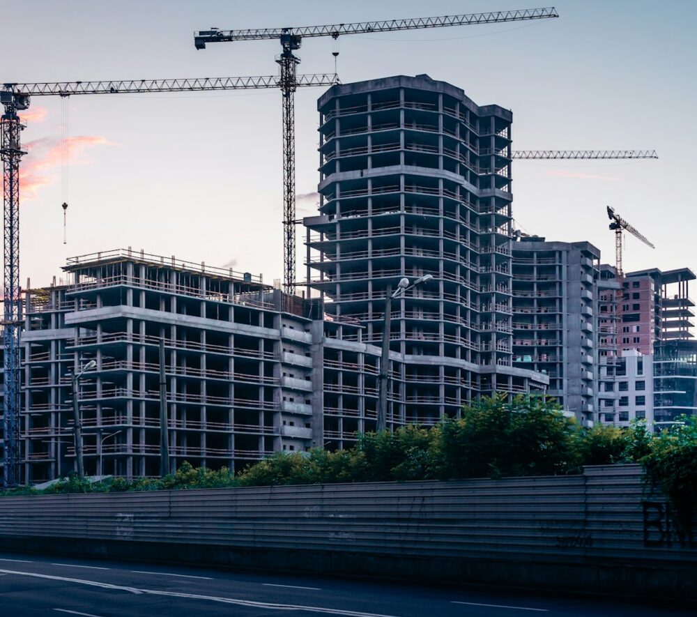 Plac budowy z powstającymi budynkami i żurawiami budowlanymi na tle miasta,fot: Anatolii Nesterov/ Unsplash