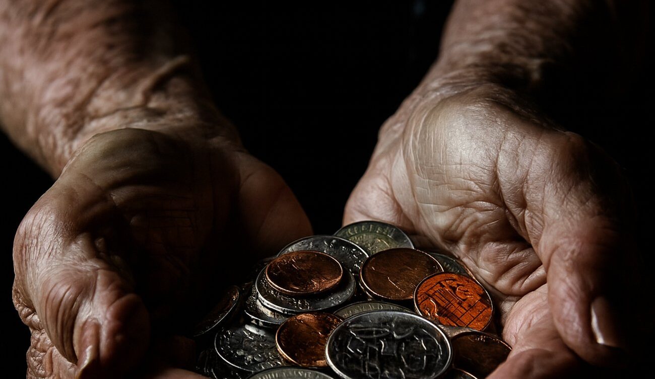 Dłonie starszego mężczyzny trzymające kilka drobnych monet