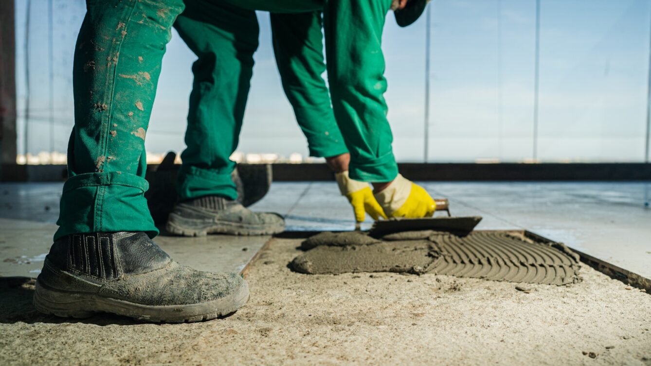 Pracownik kładzie płytki podłogowe. Praca tymczasowa dla agencji ma swoje ograniczenia. fot: Wesley Pacífico/ Unsplash