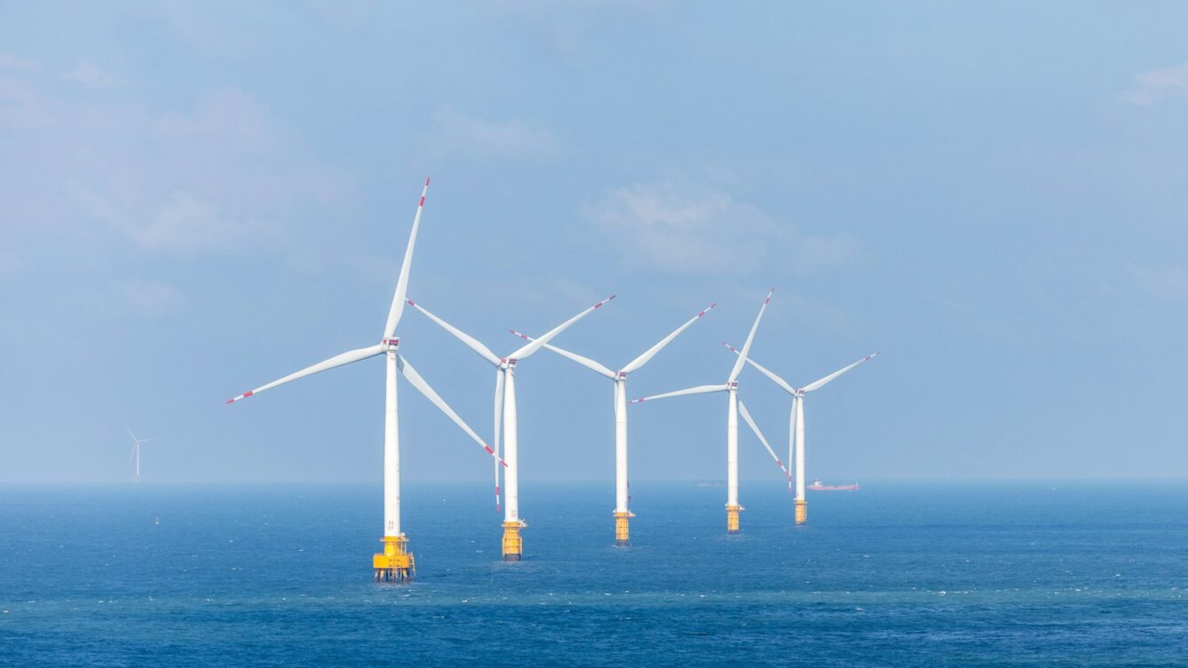 a row of wind turbines in the middle of the ocean