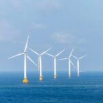 a row of wind turbines in the middle of the ocean