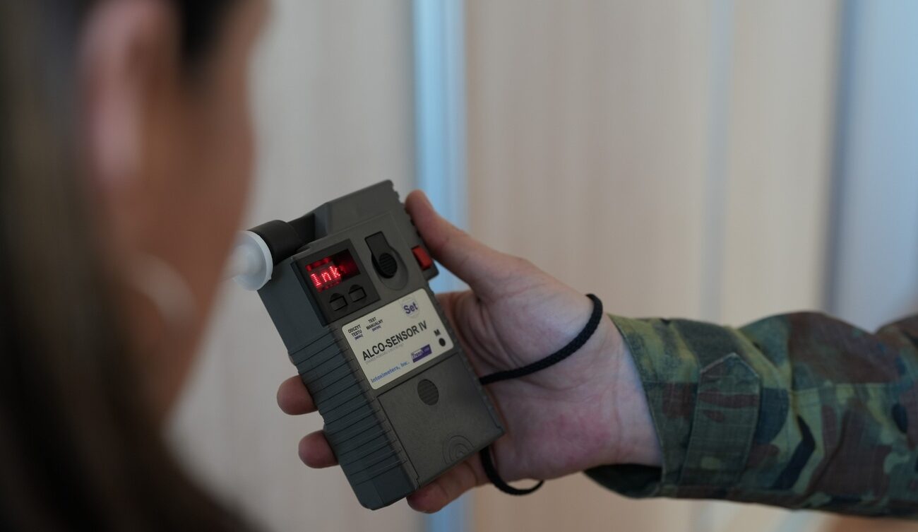 Funkcjonariusz Straży Granicznej sprawdzający trzeźwość pasażerki samolotu/ SG