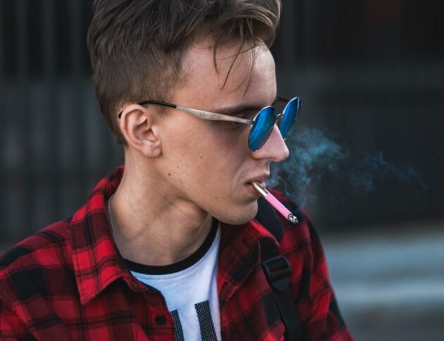 Młodzieniec palący e-papierosa. fot: Dzmitry Dudov/Unsplash