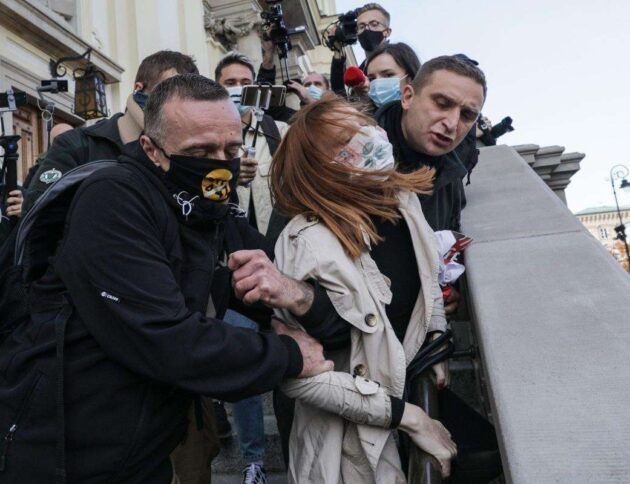 Ośrodek Monitorowania Zachowań Rasistowskich i Ksenofobicznych (OMZRiK), który wspiera oskarżycielkę: „Podczas protestów w Warszawie Robert Bąkiewicz i jego bojówkarze siłą wynieśli kobietę z kościoła św. Krzyża, a następnie zrzucili ją ze schodów. Pani Angelika uderzyła głową o beton i straciła przytomność”.