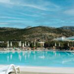 Resort swimming pool with lounge chairs and mountains.