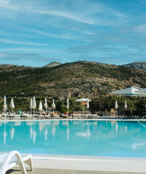 Resort swimming pool with lounge chairs and mountains.