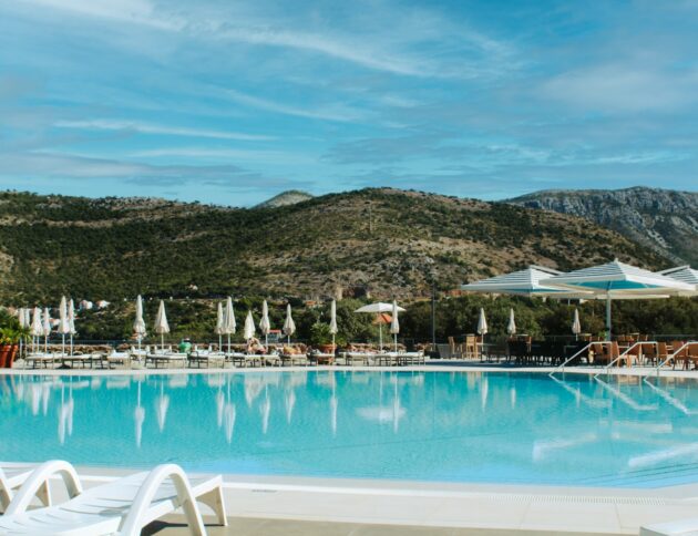 Resort swimming pool with lounge chairs and mountains.