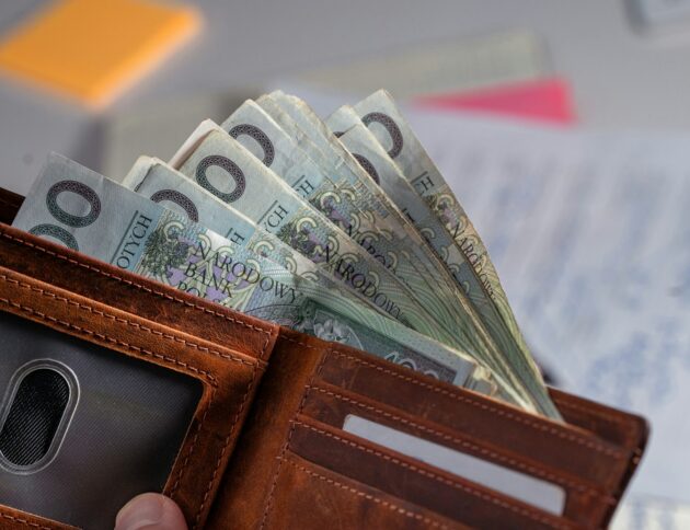 Brown leather wallet stuffed with polish currency.