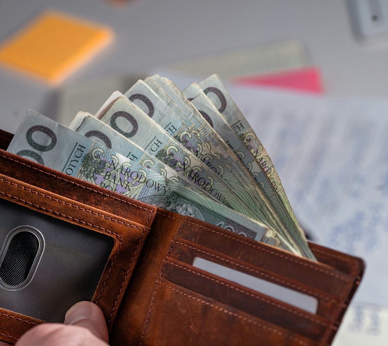 Brown leather wallet stuffed with polish currency.