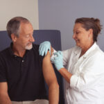 Pielęgniarka podczas szczepienie pacjenta. Autorstwa Rhoda Baer (Photographer) - This image was released by the National Cancer Institute, an agency part of the National Institutes of Health, with the ID 8215 (image) (next)., Domena publiczna
