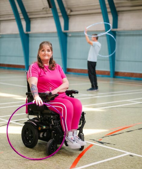 Woman in wheelchair with hula hoop, man in background