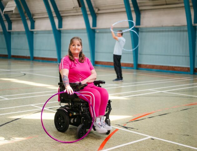 Woman in wheelchair with hula hoop, man in background