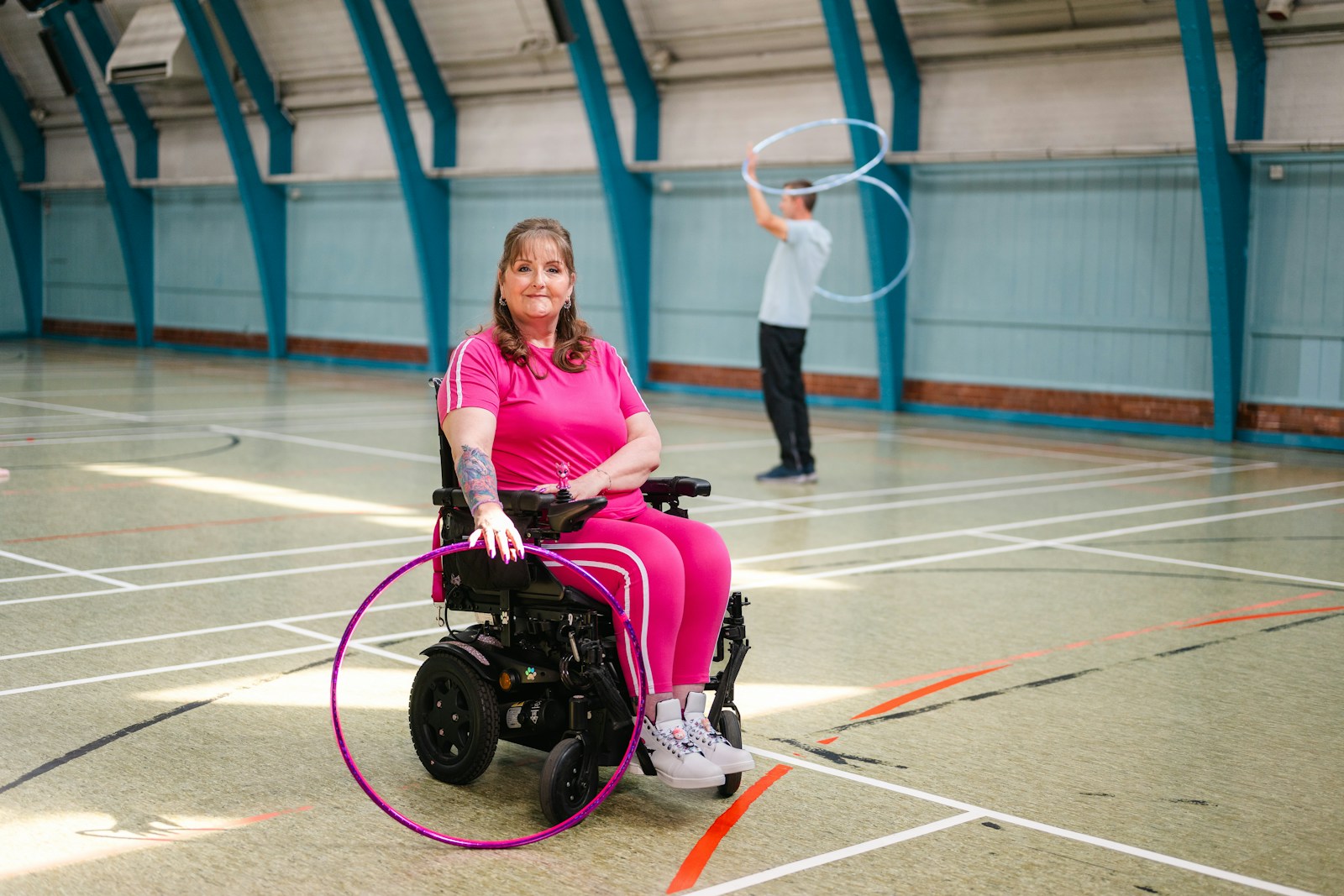 Woman in wheelchair with hula hoop, man in background