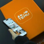 Person holding phone with temu logo box