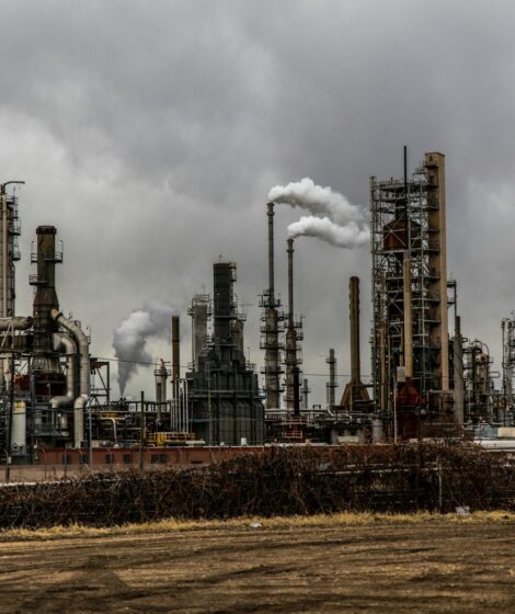 factories with smoke under cloudy sky