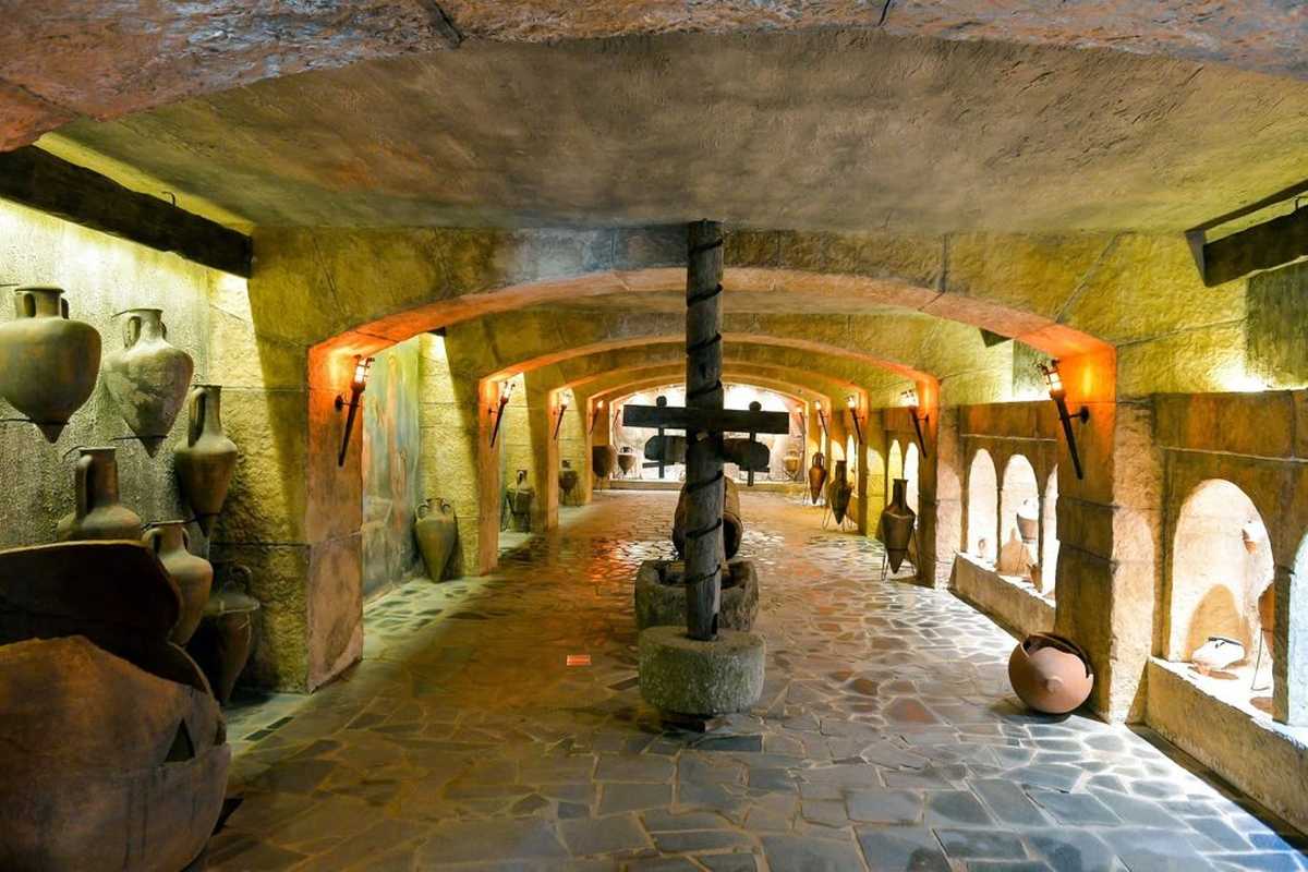 Rekonstrukcja gruzińskiej winnicy (marani) z zakopanymi w podłodze kvevri oraz satsnakheli – gruzińska kadź do tłoczenia moszczu, z której przelewano go do kvevri. Fot. Prometheus Wine Museum Georgia