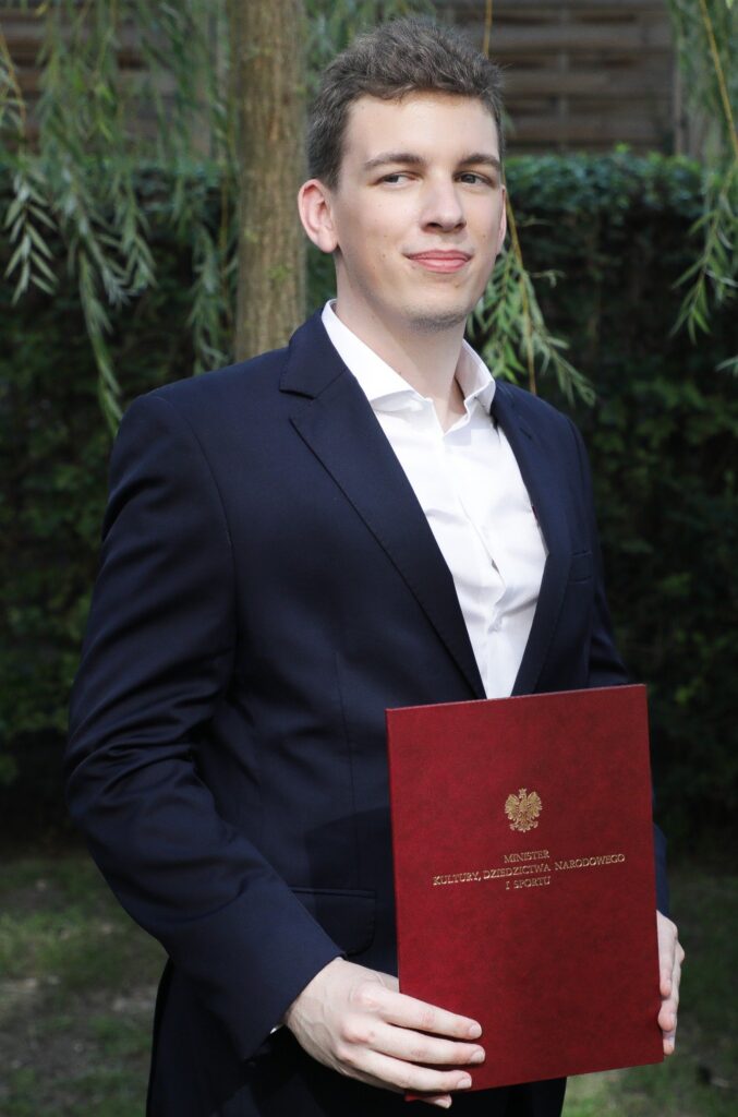młody mężczyzna w garniturze z dyplomem w ręce