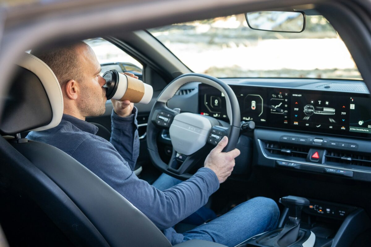 A man driving a car with a cup in his hand