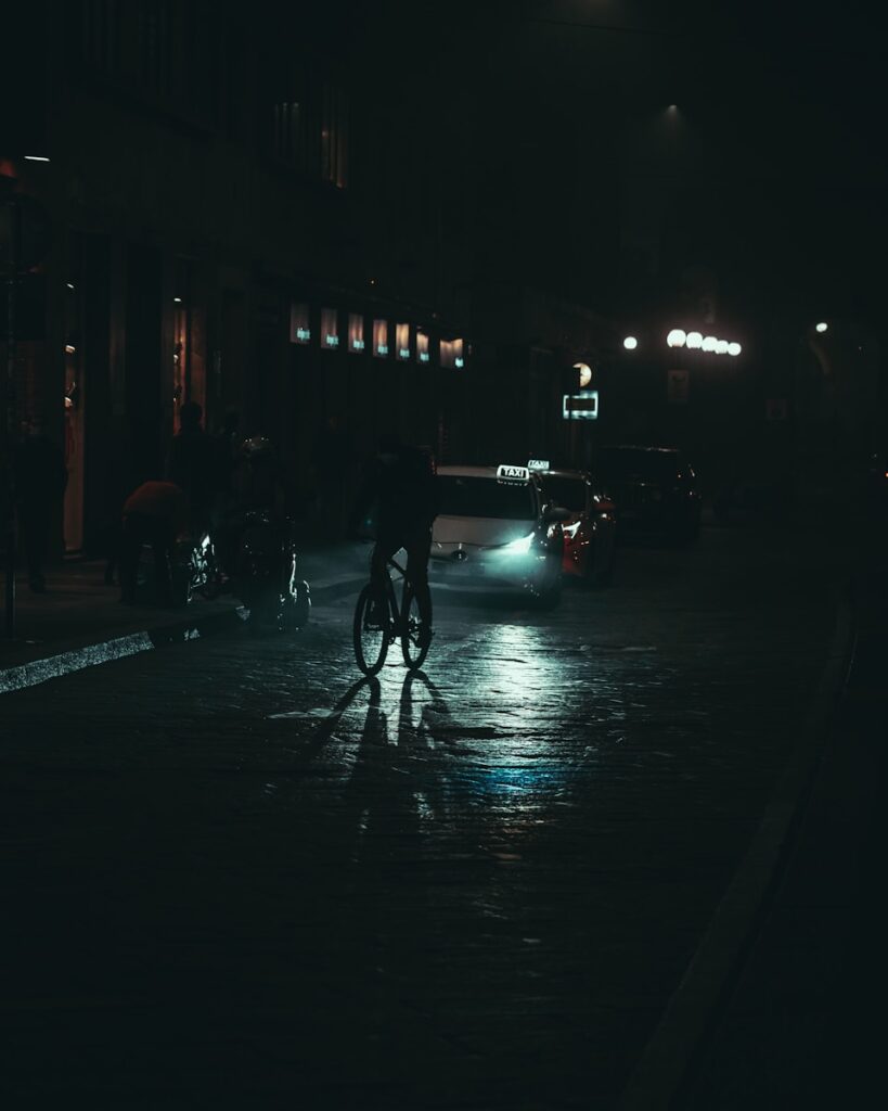 rowerzysta jadący bez oświetlenia po ulicy/ fot: Mikita Yo/Unsplash